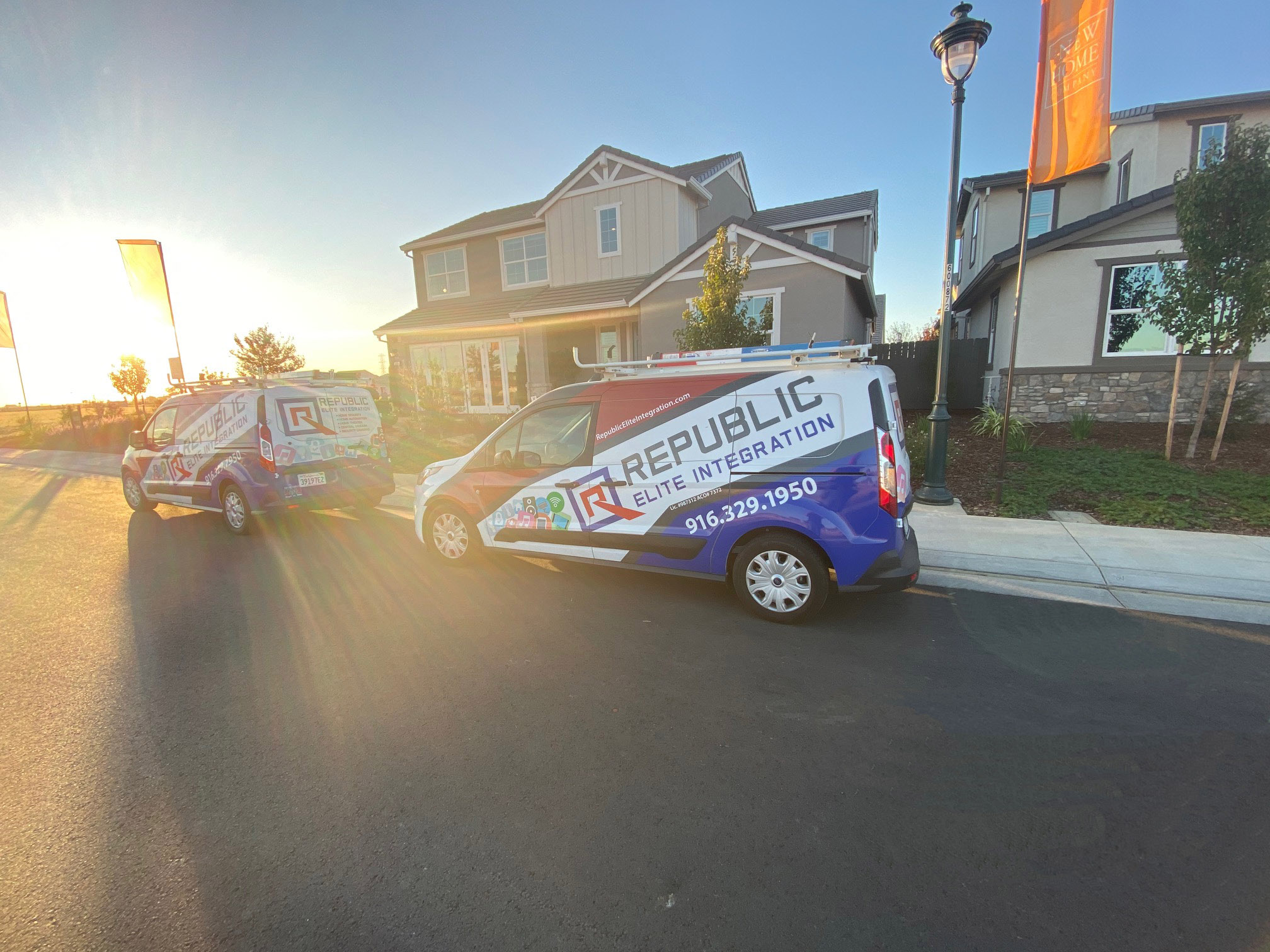 REI Vans in front of model home with sunrise behind them