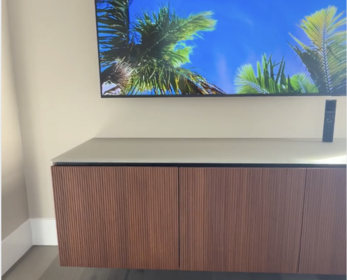 Wall-mounted TV above a Salamander floating cabinet with a modern slatted wood finish in a contemporary living space.